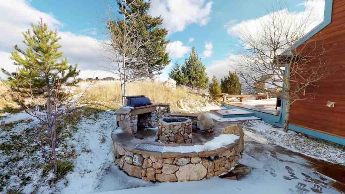 Stone fire pit in winter with pine trees